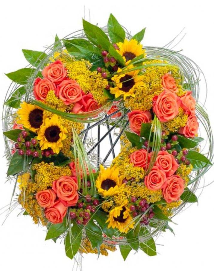 Corona de flores funeraria con girasoles y rosas.
